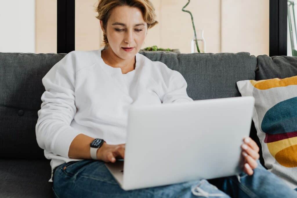 Woman in a white sweater working on a laptop