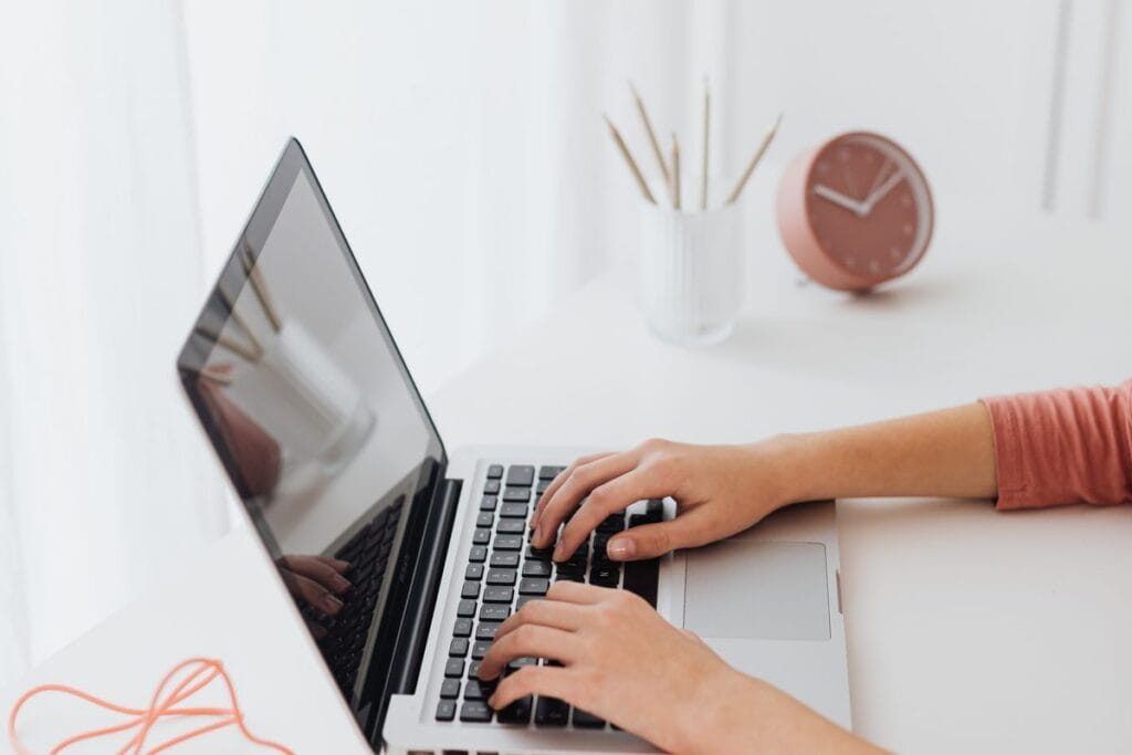 Hands typing on a laptop at a clean minimal desk