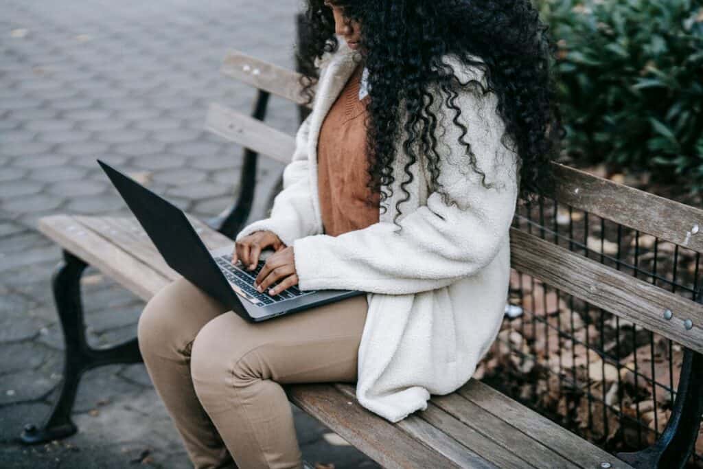 Woman working on a laptop on a park bench