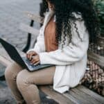 Woman working on a laptop on a park bench