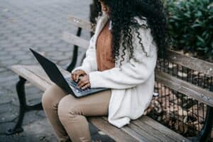 Woman working on a laptop on a park bench