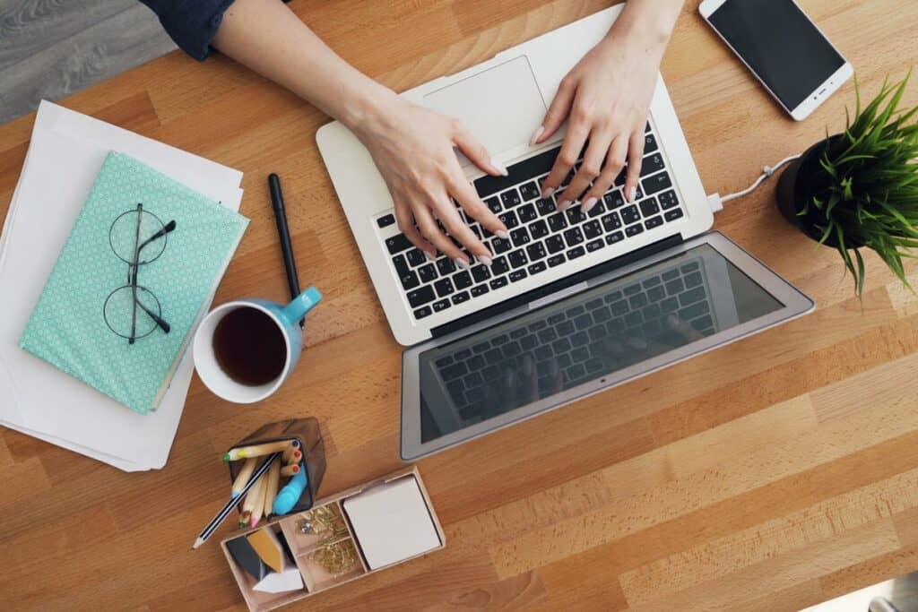 Overhead view of a laptop and coffee on a wood desk