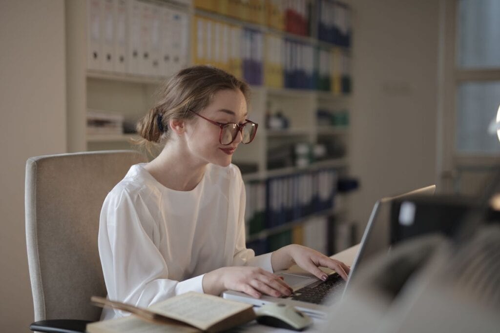 Woman at a desk with a laptop and open reference book