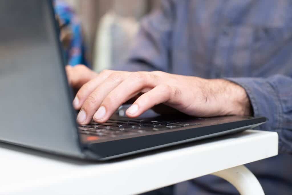 Close-up of hands typing on a laptop