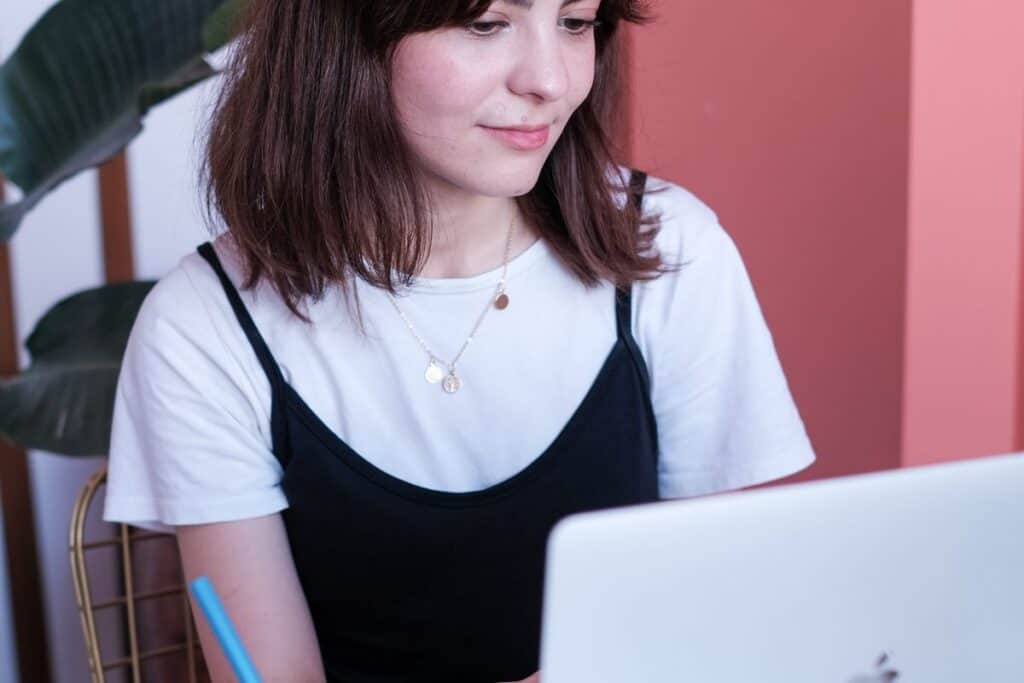 Woman writing while working at a laptop